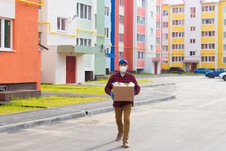 the volunteers walk down the street with a box of groceries